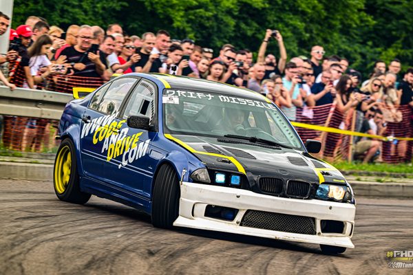 BMW E46 drifting past the crowd with the front wheels at full lock